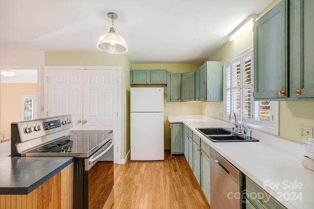 kitchen with sink, green cabinetry, light hardwood / wood-style flooring, decorative light fixtures, and stainless steel appliances