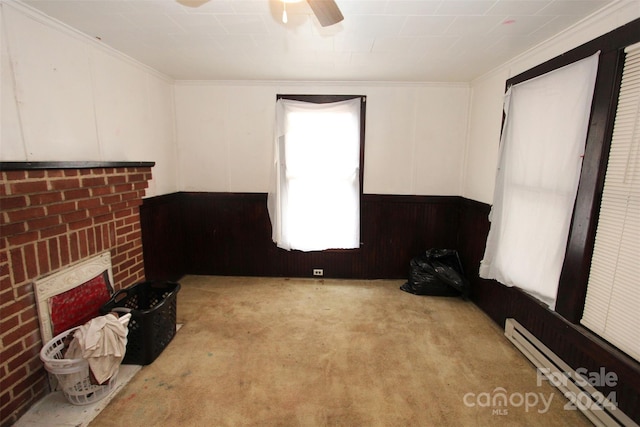 interior space featuring a baseboard radiator, ceiling fan, crown molding, and wood walls