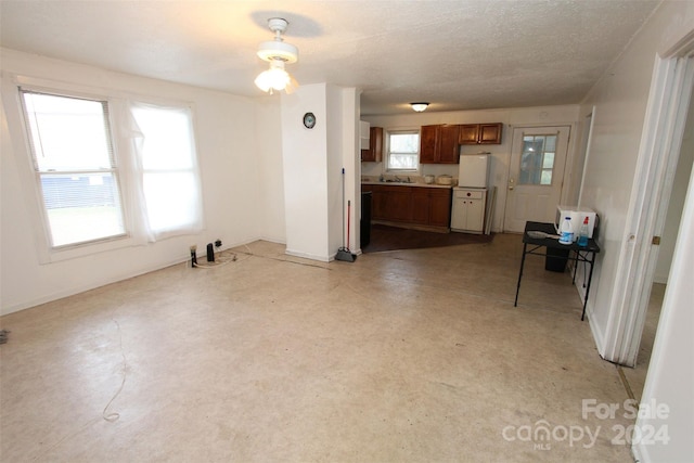 interior space with a textured ceiling, white fridge, and sink