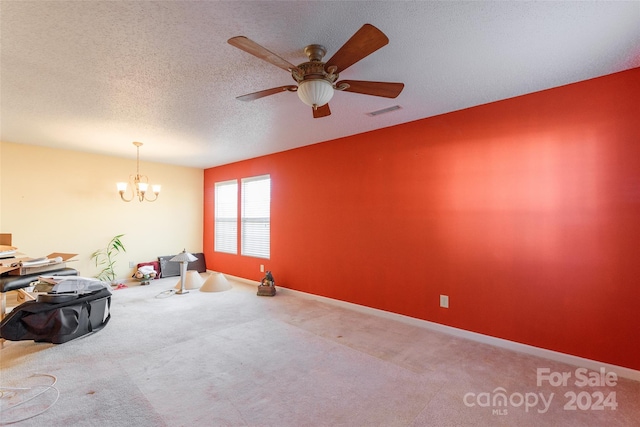 carpeted spare room with ceiling fan with notable chandelier and a textured ceiling