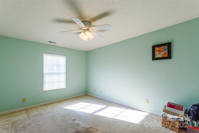 carpeted spare room featuring a textured ceiling and ceiling fan