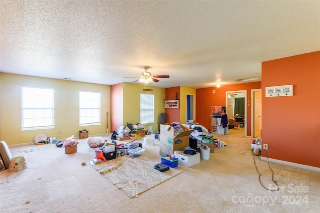 carpeted living room with ceiling fan and a textured ceiling