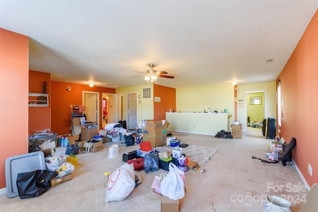 living room featuring ceiling fan, carpet floors, and a textured ceiling