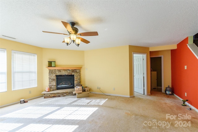 unfurnished living room with ceiling fan, a fireplace, light colored carpet, and a textured ceiling