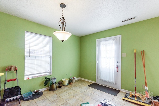 doorway to outside with light tile patterned flooring and a textured ceiling