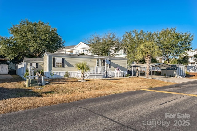 view of front of home with a front yard, a carport, and a storage unit