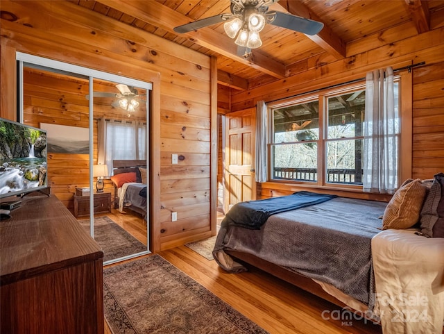 bedroom featuring ceiling fan, light wood-type flooring, beam ceiling, wood ceiling, and a closet