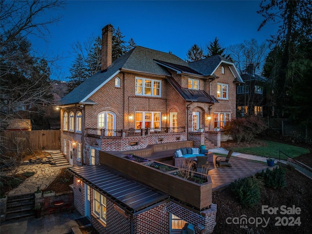 back house at twilight with a patio area and an outdoor hangout area