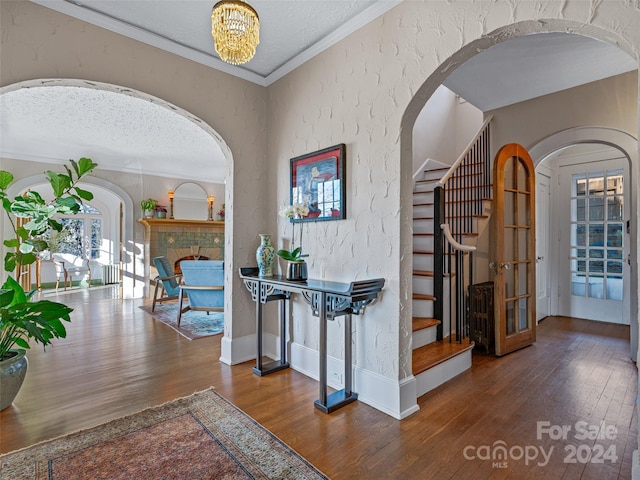 corridor with a textured ceiling, crown molding, dark wood-type flooring, and french doors