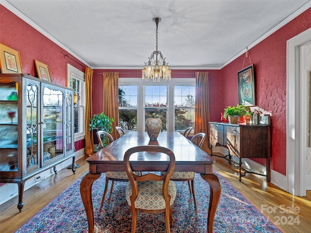 dining room featuring a textured ceiling, light hardwood / wood-style floors, crown molding, and a chandelier