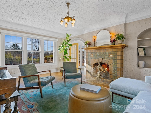 living room featuring a tiled fireplace, hardwood / wood-style floors, a textured ceiling, and a notable chandelier