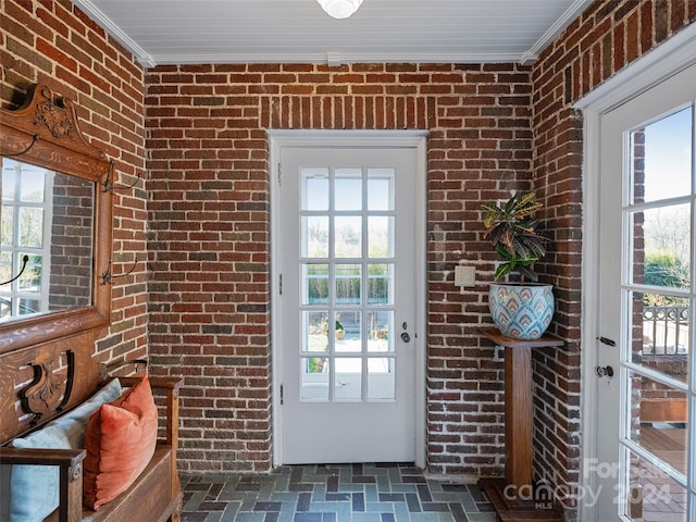 doorway to outside with a healthy amount of sunlight, crown molding, and brick wall