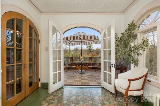 doorway to outside with french doors, a textured ceiling, and crown molding