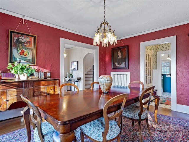 dining room with a chandelier, hardwood / wood-style floors, a textured ceiling, and crown molding