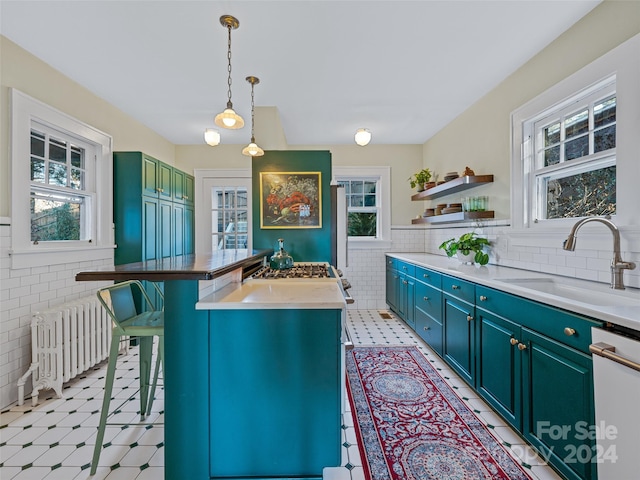 kitchen with pendant lighting, dishwasher, a center island, radiator, and sink