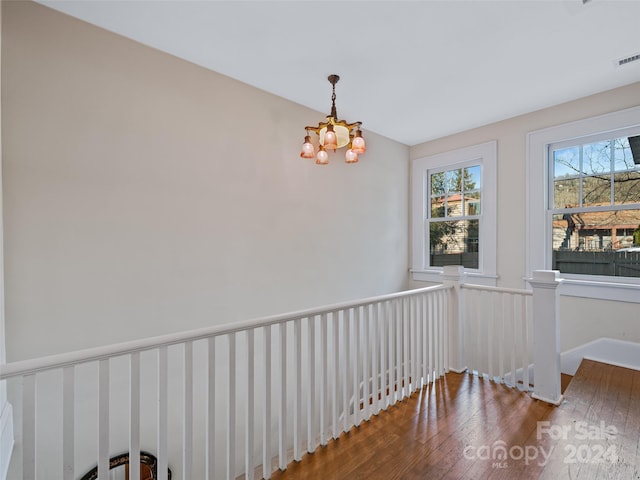 spare room with dark hardwood / wood-style floors and an inviting chandelier