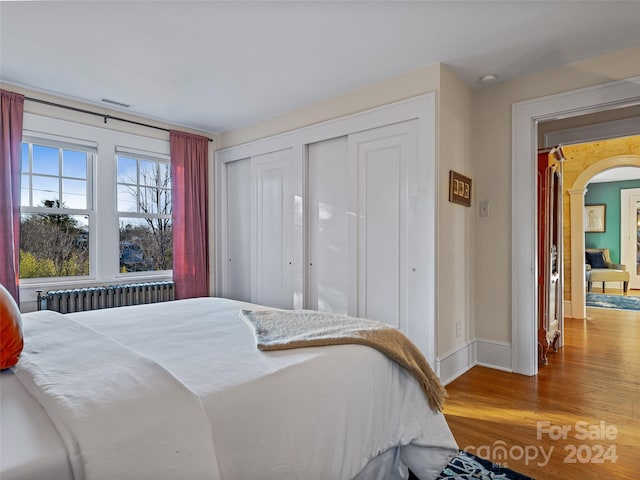 bedroom with radiator heating unit and hardwood / wood-style flooring