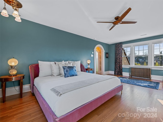 bedroom featuring ceiling fan, radiator heating unit, and hardwood / wood-style flooring