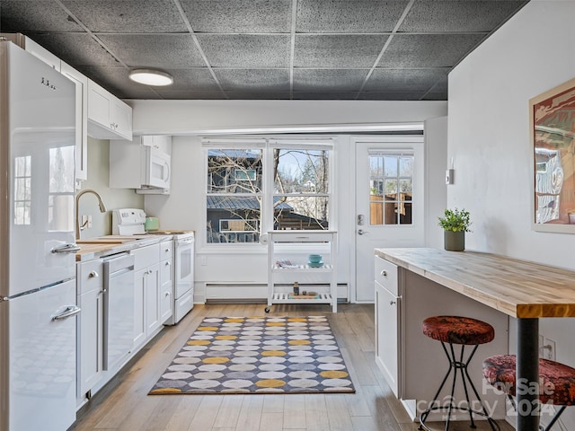 kitchen with white cabinets, white appliances, butcher block countertops, and light hardwood / wood-style floors