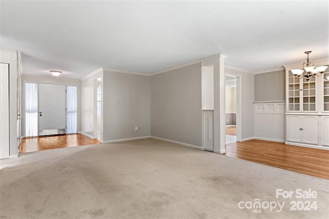 unfurnished living room with wood-type flooring, crown molding, and an inviting chandelier