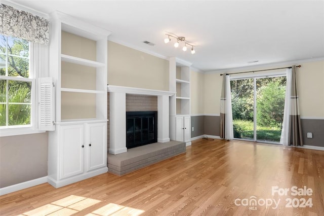 unfurnished living room with built in features, light hardwood / wood-style floors, a brick fireplace, and crown molding