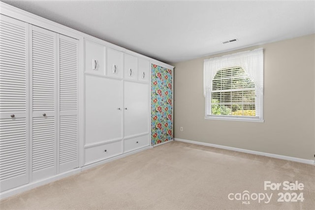 unfurnished bedroom featuring light carpet and a closet