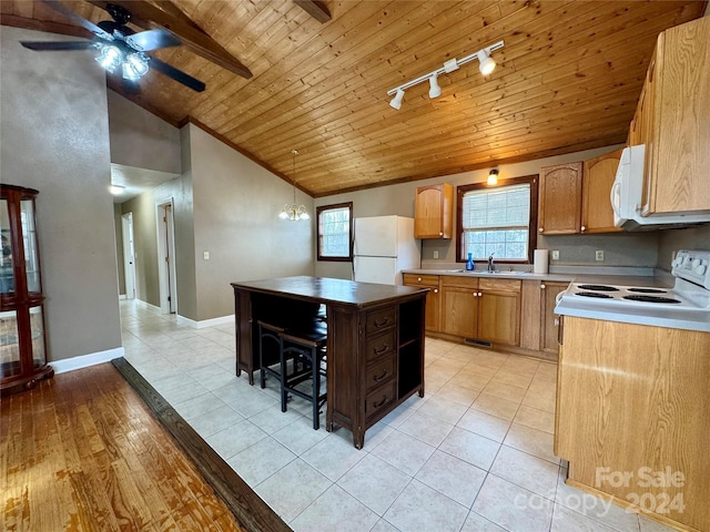 kitchen featuring lofted ceiling, a healthy amount of sunlight, white appliances, and hanging light fixtures