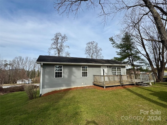 rear view of house featuring a lawn and a wooden deck