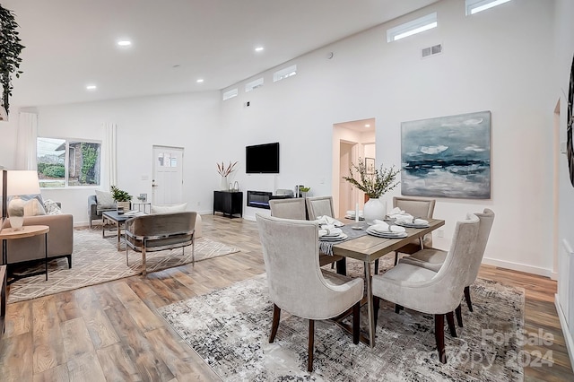 dining area with light hardwood / wood-style floors and high vaulted ceiling