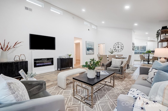 living room featuring light hardwood / wood-style flooring and a towering ceiling