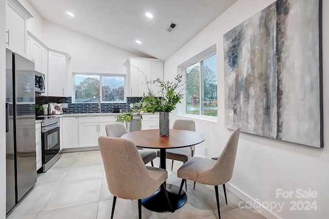 dining space featuring sink, light tile patterned flooring, and lofted ceiling