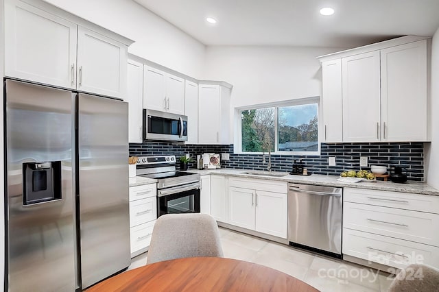 kitchen featuring appliances with stainless steel finishes, tasteful backsplash, vaulted ceiling, sink, and white cabinetry