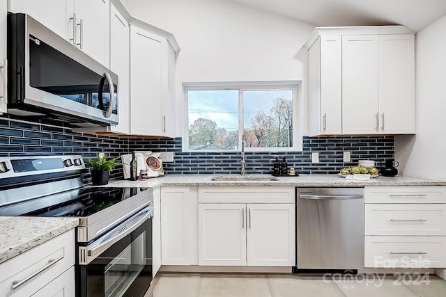 kitchen with light stone countertops, stainless steel appliances, white cabinetry, and sink