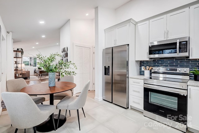 kitchen with light stone countertops, white cabinetry, and stainless steel appliances