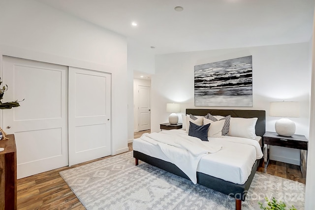 bedroom with a closet, wood-type flooring, and vaulted ceiling