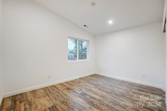 empty room featuring wood-type flooring and lofted ceiling