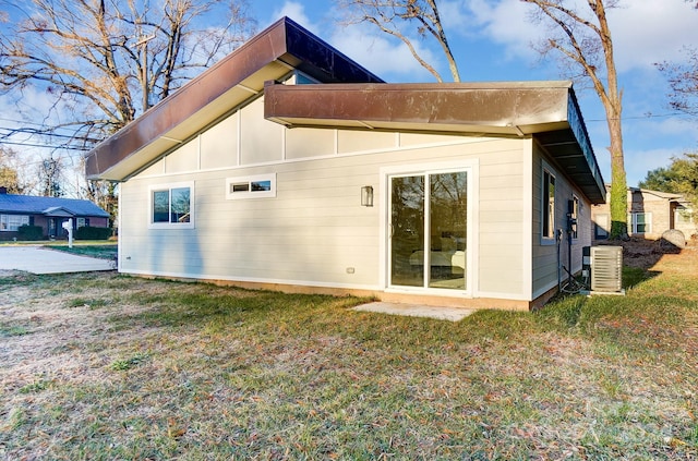 rear view of house with a lawn and central AC unit