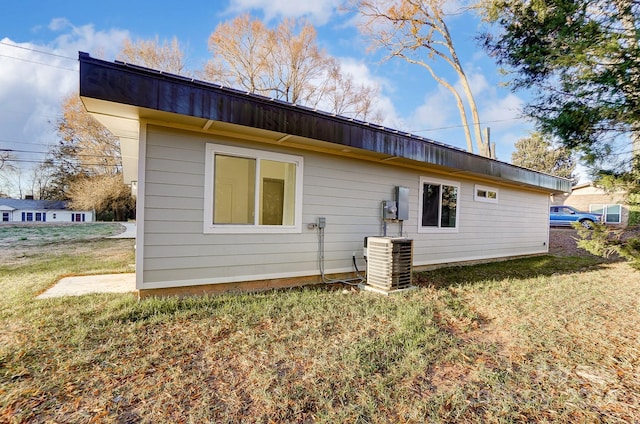 back of house featuring central air condition unit and a yard