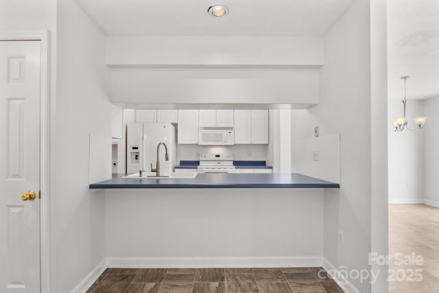 kitchen with kitchen peninsula, pendant lighting, white appliances, and white cabinetry