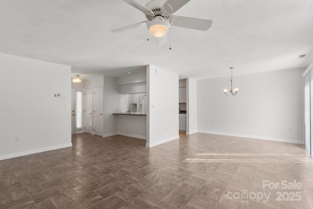 unfurnished living room featuring ceiling fan with notable chandelier