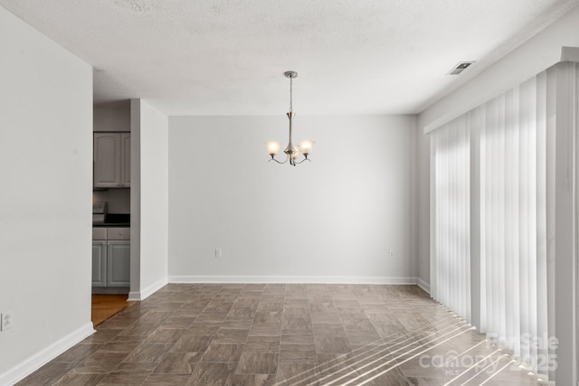 unfurnished room featuring a textured ceiling and an inviting chandelier