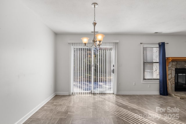 unfurnished dining area featuring a fireplace and an inviting chandelier