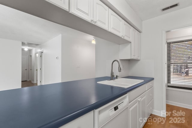 kitchen featuring dark hardwood / wood-style flooring, a textured ceiling, white dishwasher, sink, and white cabinets