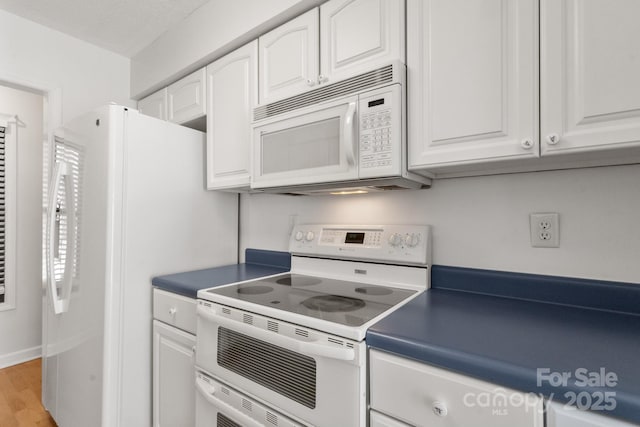 kitchen with white cabinets, light wood-type flooring, and white appliances