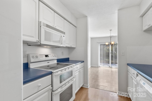 kitchen featuring white appliances, white cabinets, hanging light fixtures, light hardwood / wood-style flooring, and a notable chandelier