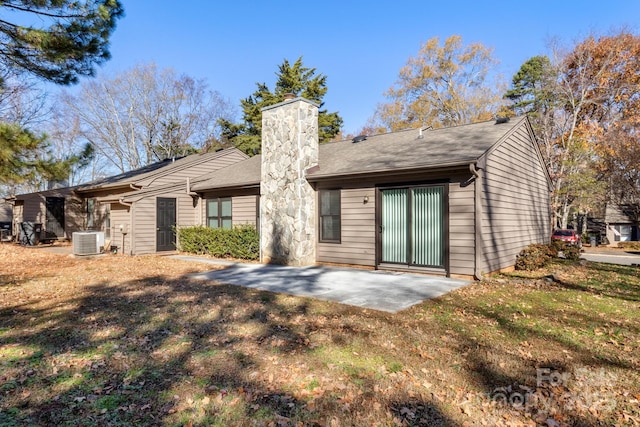 rear view of house with central AC unit, a patio area, and a lawn