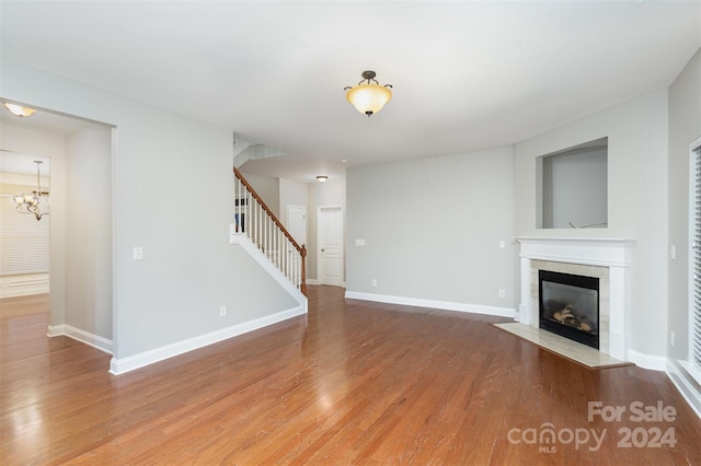 unfurnished living room with a notable chandelier, wood-type flooring, and a fireplace