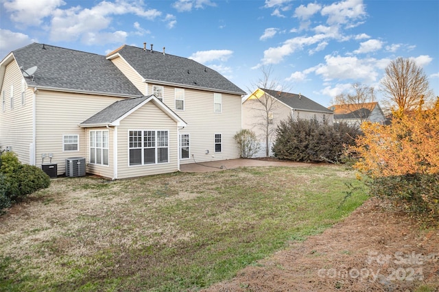 rear view of property with cooling unit, a yard, and a patio