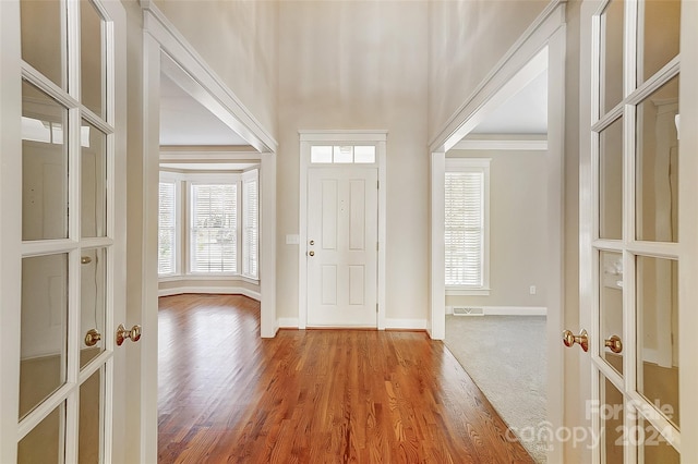 entryway with hardwood / wood-style flooring, crown molding, and french doors