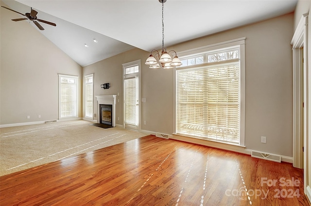 unfurnished living room featuring ceiling fan with notable chandelier, a healthy amount of sunlight, and high vaulted ceiling